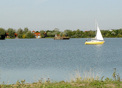 Segelschiff und Kiesschute auf dem See
